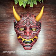 a red mask with yellow horns on top of a wooden table