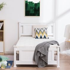 a white bed sitting in a bedroom on top of a hard wood floor next to a book shelf