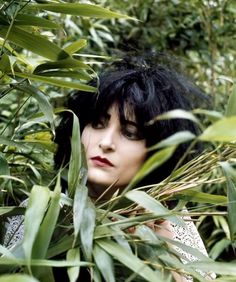 a woman with black hair is hiding in the bushes