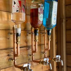 there are three different types of water in the glass bottles on the wall above the faucets