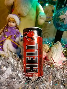 a can of beer sitting on top of tinsel next to a stuffed animal and christmas tree