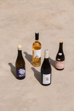 three bottles of wine sitting next to each other on a cement surface with no one around them