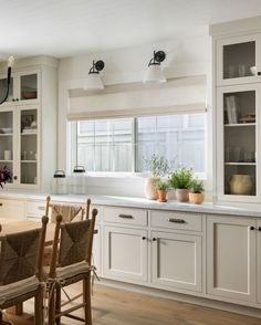 a kitchen with white cabinets and wooden chairs