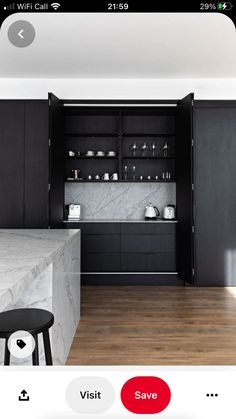 a kitchen with black cabinets and marble counter tops, along with a bar stool in the center