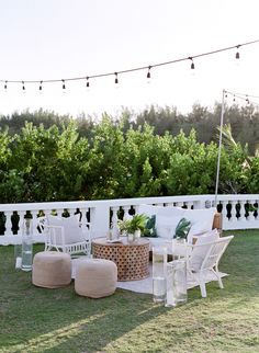 an outdoor patio with white furniture and string lights