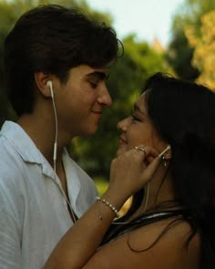 a man and woman standing next to each other with ear buds in their ears looking at each other