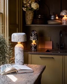 an open book sitting on top of a wooden table next to a vase filled with flowers