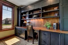 a home office with built - in desk and bookcases next to a large window