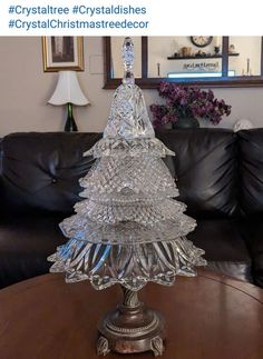 a glass christmas tree sitting on top of a table in front of a black couch