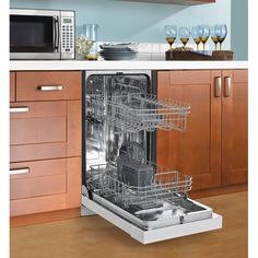 an open dishwasher in a kitchen with wooden cabinets