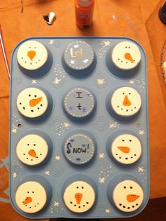 there are twelve cupcakes in the shape of snowmen on this blue tray