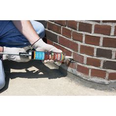 a man is working on a brick wall with an electric screwdriver in his hand