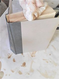 an old book is sitting on top of a table with a cloth draped over it