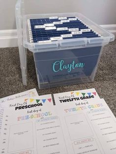 a clear plastic box filled with blue binders next to a white wall and carpeted floor