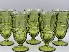 six green glass goblets sitting side by side