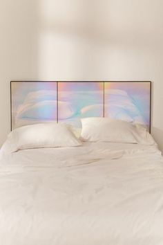 a bed with white sheets and pillows in a room next to a wall mounted headboard