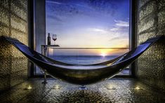 a hammock hanging in front of a window overlooking the ocean at sunset or sunrise