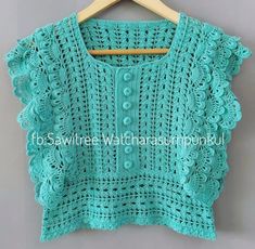 a green crocheted top hanging on a wooden hanger