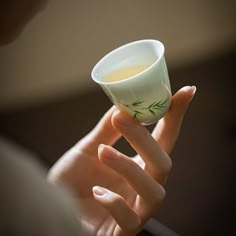 a woman is holding a cup in her hand with some green sprigs on it