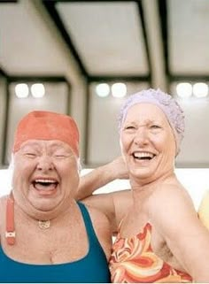 two older women are laughing and posing for the camera with their heads covered by towels