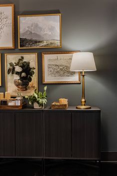 a living room with pictures on the wall and a table lamp in front of it