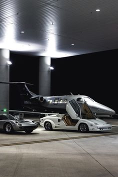 two cars are parked in front of an airplane and a car with the door open