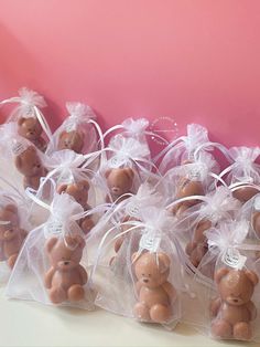 small brown teddy bears wrapped in clear plastic bags on a pink surface with white ribbons