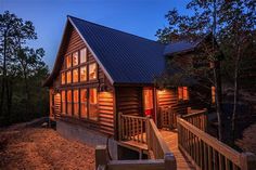 a log cabin with stairs leading up to the front door and porch area at night