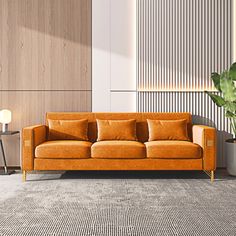 an orange couch sitting on top of a rug next to a table with a potted plant