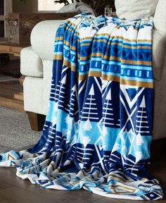 a blue and white blanket sitting on top of a couch next to a vase with flowers