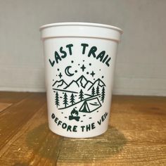 a white cup with the words last trail before the view on it sitting on a wooden table