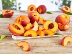 a white plate topped with sliced peaches on top of a wooden table