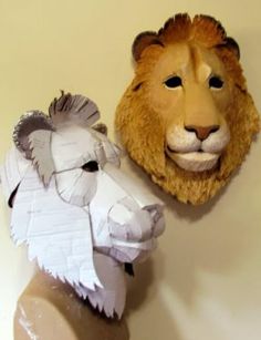 two paper mache lion heads on top of each other, one is white and the other is brown