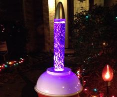 a purple and white light is on top of a red container in front of a house