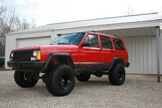 a red jeep parked in front of a garage