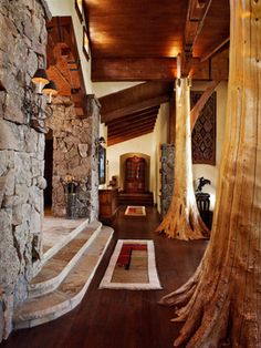 the inside of a house with wood floors and stone walls, along with an area rug that looks like a tree trunk