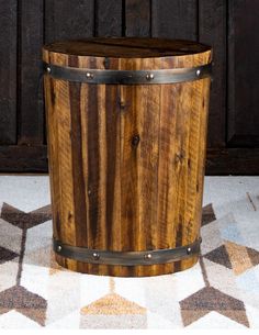 a wooden barrel sitting on top of a white and brown rug next to a wall