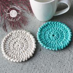 two crocheted coasters sitting next to a coffee cup