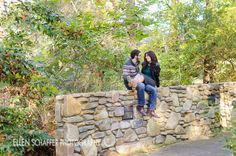 two people are sitting on a stone wall