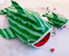 a watermelon shaped stuffed animal laying on top of a white bed covered in candy