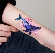 a woman's arm with a tattoo on it that has a whale and stars