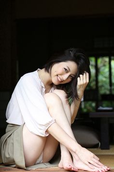 a woman is sitting on the floor with her legs crossed and hands behind her head