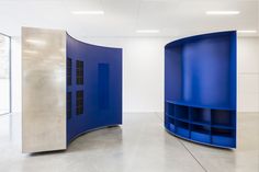 an empty room with two curved blue shelves and a white wall in the background,