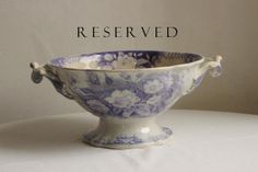 a blue and white flowered bowl on a table with the words reserved above it