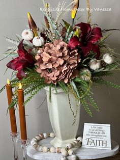 a white vase filled with lots of flowers on top of a table next to candles