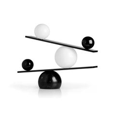 three balls are balanced on top of each other in the same direction, with one black and one white ball at the end