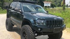 a black jeep parked on the side of a dirt road