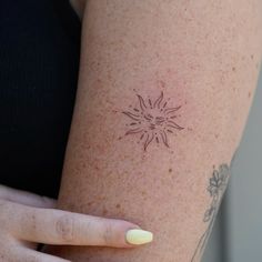 a woman's arm with a sun tattoo on the back of her left arm