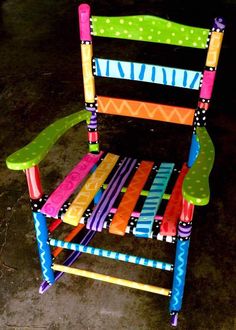 a brightly colored wooden chair sitting on top of a cement floor