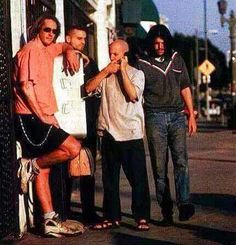 three men standing on the side of a road next to each other and one man holding his hand up